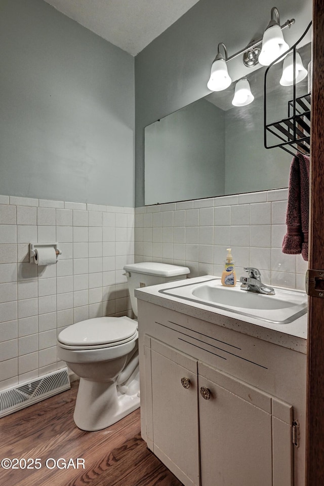 bathroom with tile walls, visible vents, wood finished floors, and toilet