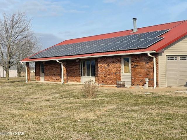 rear view of property featuring brick siding, a lawn, and roof mounted solar panels