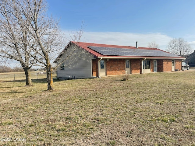 ranch-style home with brick siding, roof mounted solar panels, and a front yard