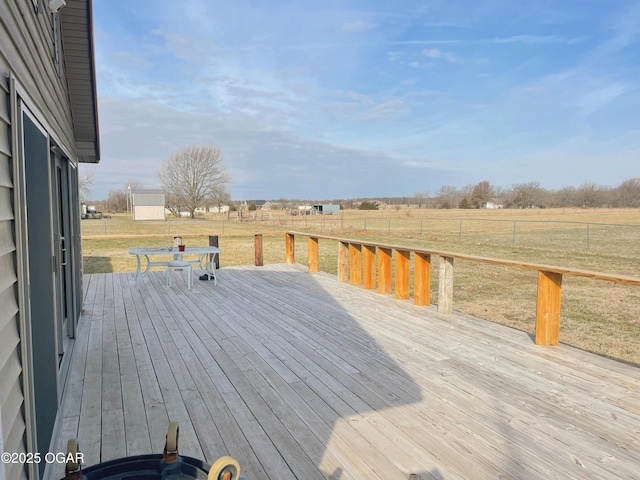 wooden terrace featuring a yard, a rural view, and fence