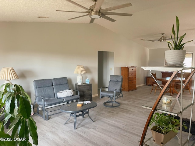 living area featuring a ceiling fan, lofted ceiling, baseboards, and light wood finished floors