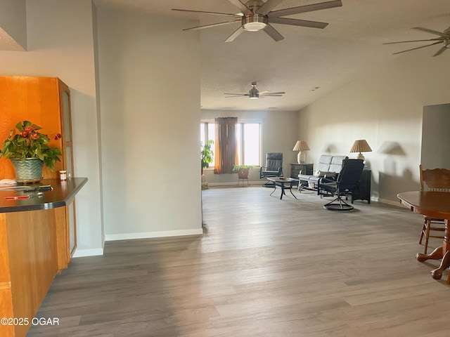 sitting room featuring a ceiling fan, a textured ceiling, wood finished floors, high vaulted ceiling, and baseboards