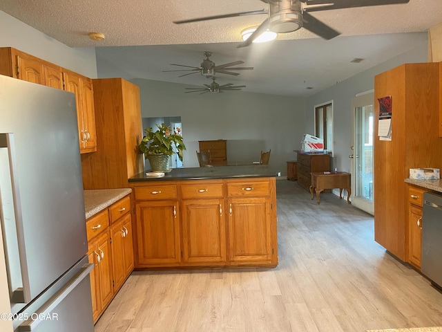 kitchen featuring a textured ceiling, a peninsula, appliances with stainless steel finishes, light wood-type flooring, and brown cabinets