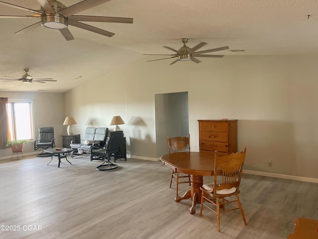 dining space featuring baseboards, vaulted ceiling, a textured ceiling, and light wood finished floors