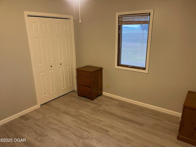 unfurnished bedroom with a closet, wood finished floors, and baseboards