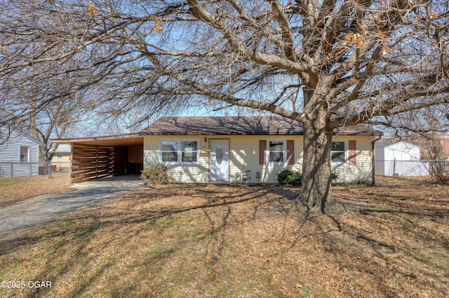 ranch-style home with a carport, a front yard, fence, and driveway