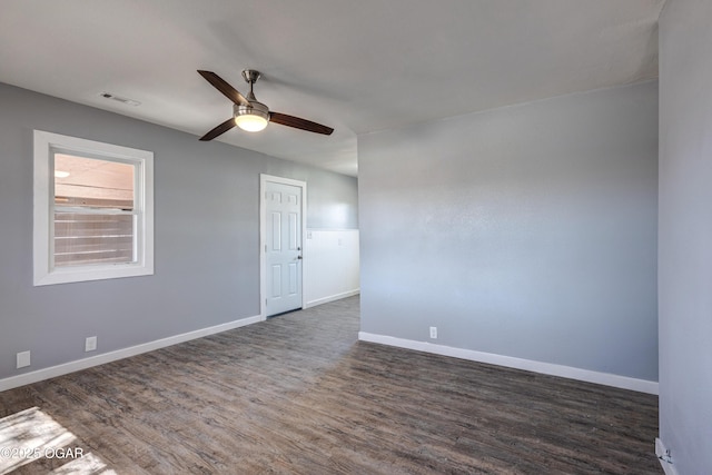 spare room featuring a ceiling fan, dark wood-style flooring, visible vents, and baseboards