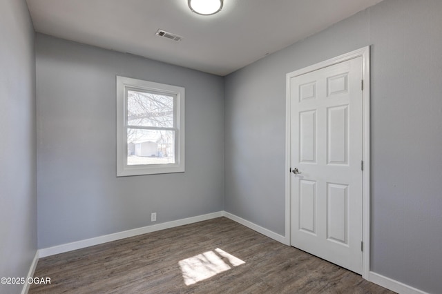 spare room featuring baseboards, visible vents, and wood finished floors