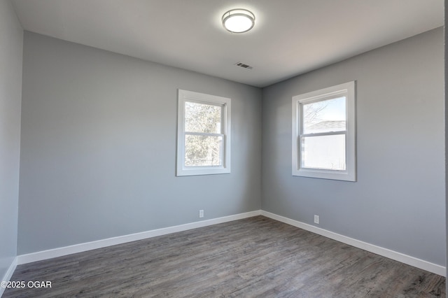 unfurnished room featuring dark wood-style floors, baseboards, and visible vents