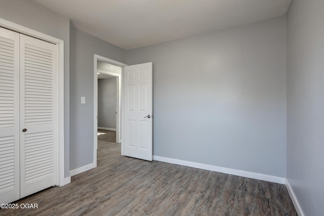 unfurnished bedroom featuring a closet, baseboards, and wood finished floors