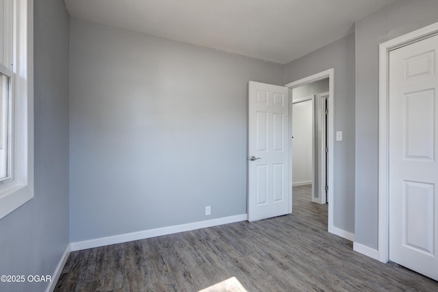 unfurnished bedroom featuring wood finished floors and baseboards