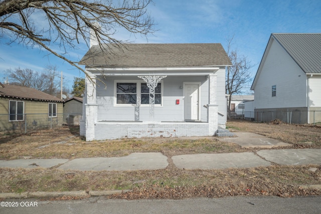 bungalow-style house featuring a porch, roof with shingles, and fence