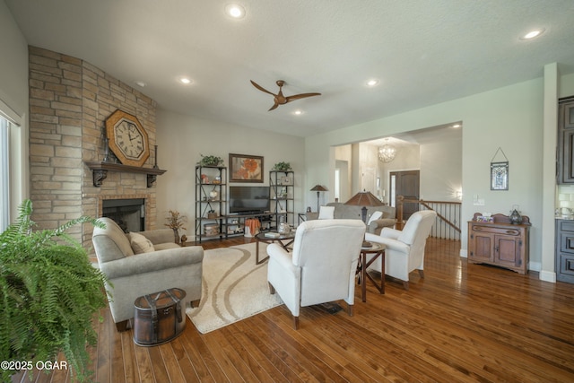 living room featuring recessed lighting, wood finished floors, a fireplace, and ceiling fan with notable chandelier