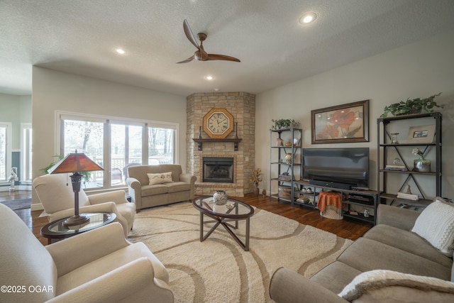 living room featuring a ceiling fan, a textured ceiling, wood finished floors, recessed lighting, and a fireplace