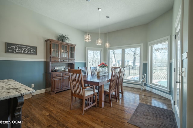 dining room with baseboards, a textured ceiling, an inviting chandelier, and dark wood finished floors