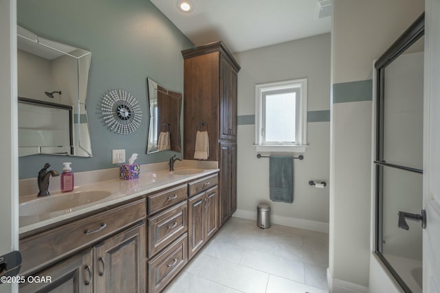 bathroom with double vanity, tile patterned floors, baseboards, and a sink