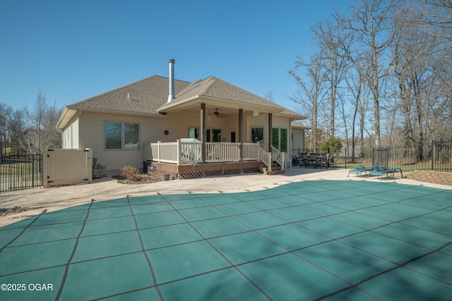 back of house featuring fence, a fenced in pool, roof with shingles, and a wooden deck