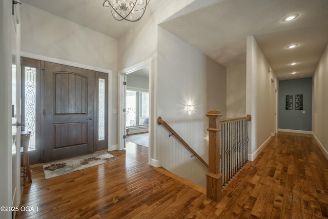 foyer entrance featuring recessed lighting, baseboards, a notable chandelier, and hardwood / wood-style flooring