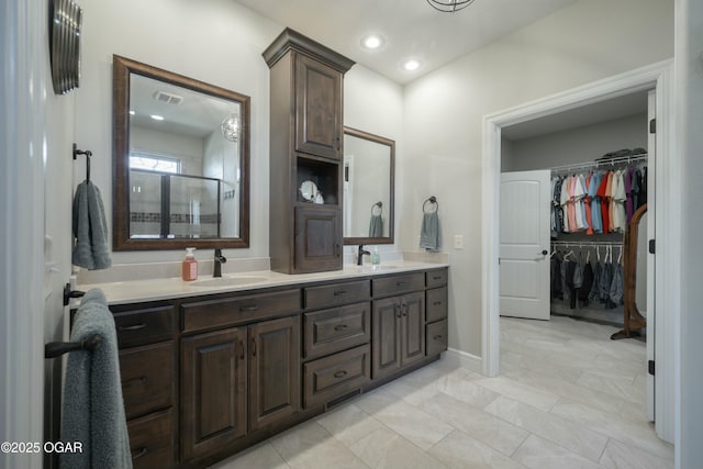 bathroom featuring a sink, a shower stall, recessed lighting, and double vanity