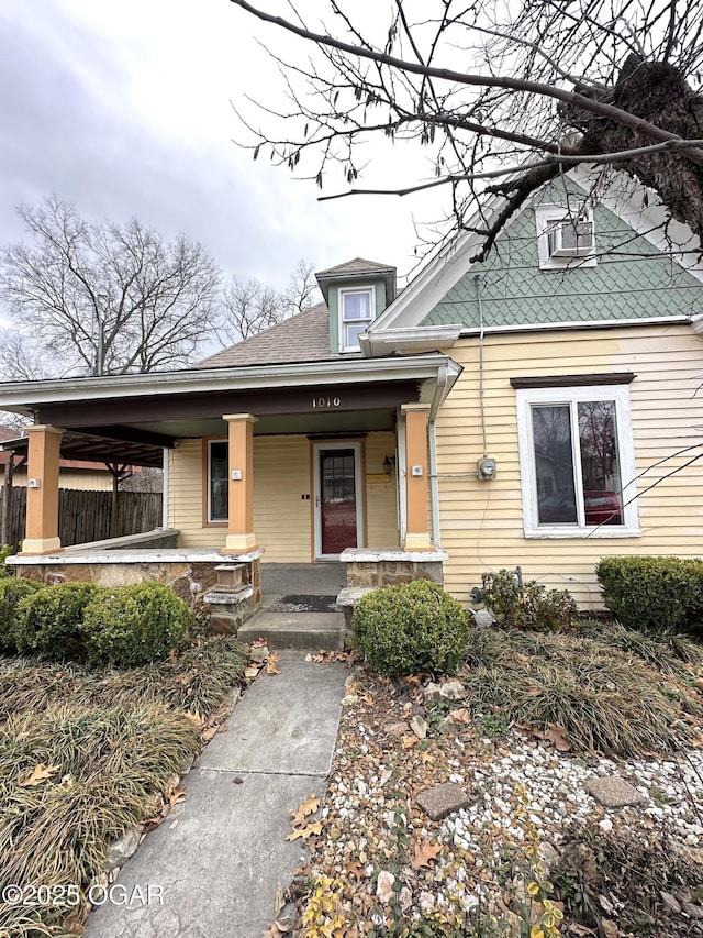 bungalow-style home featuring covered porch and fence