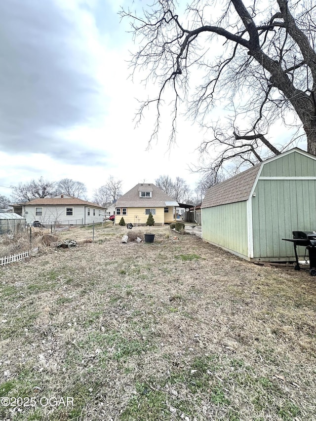 view of yard featuring a storage shed, an outbuilding, and fence