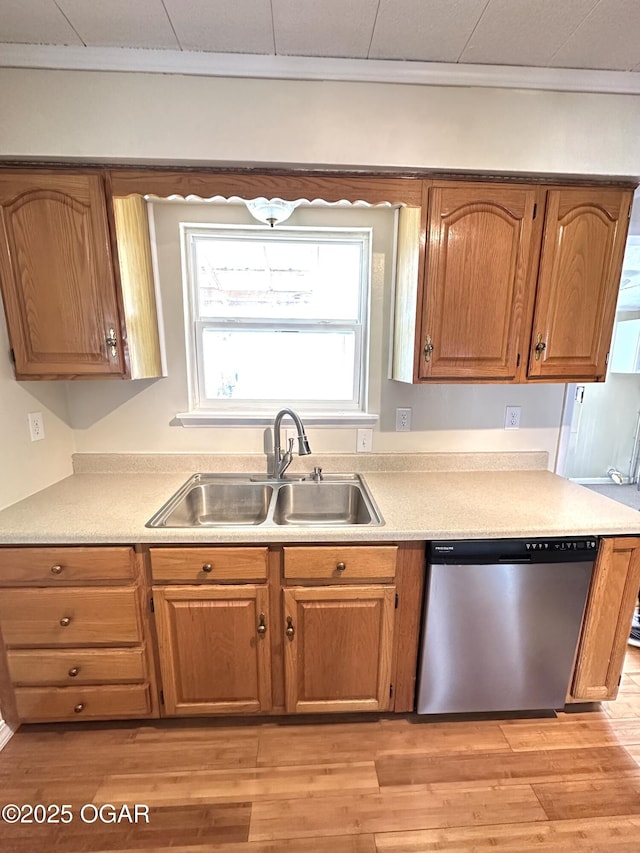 kitchen featuring stainless steel dishwasher, brown cabinetry, a sink, and light wood-style flooring