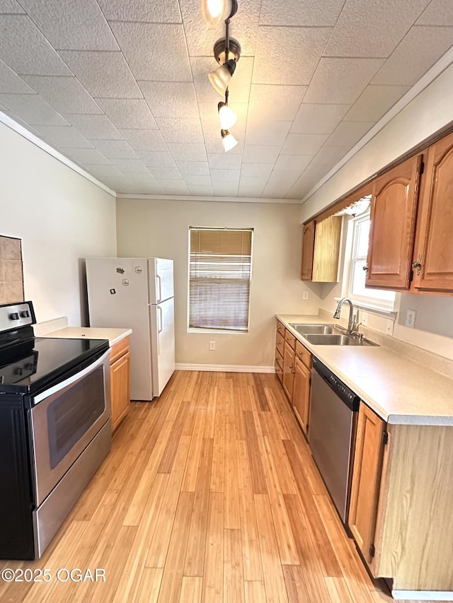 kitchen with light wood-style flooring, appliances with stainless steel finishes, brown cabinets, light countertops, and a sink