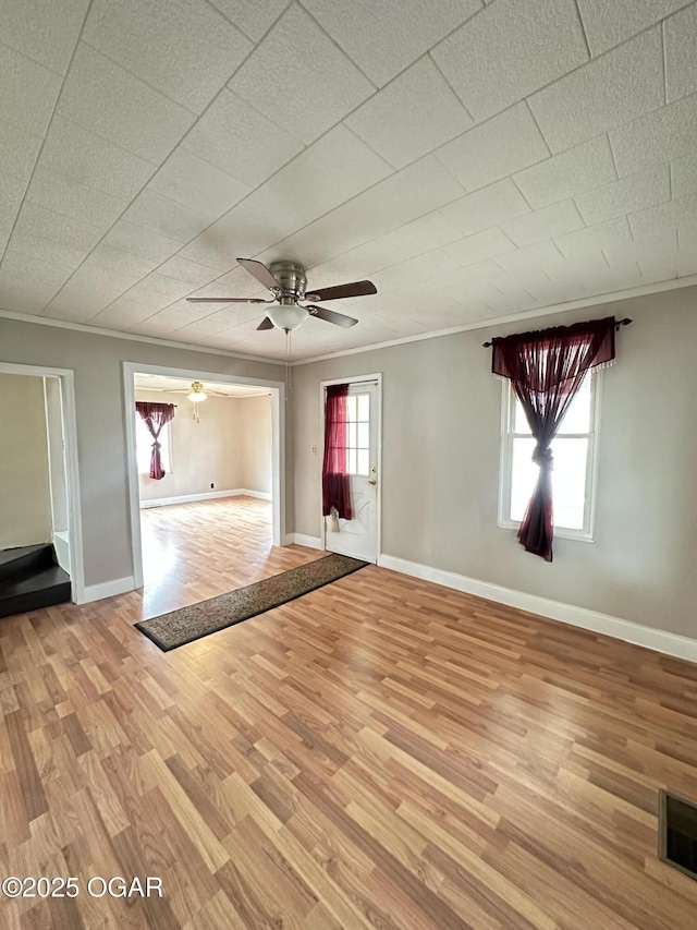 interior space featuring ornamental molding, light wood-style flooring, visible vents, and baseboards