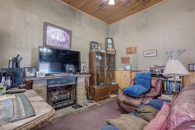 living room featuring a fireplace, a ceiling fan, wood ceiling, wainscoting, and carpet flooring