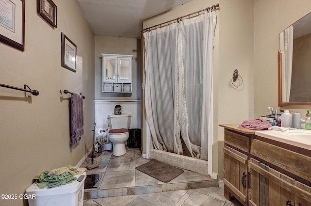 bathroom with toilet, a shower stall, vanity, tile patterned flooring, and baseboards