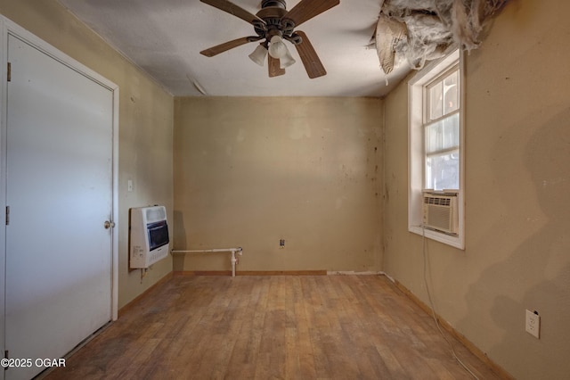 empty room with a ceiling fan, cooling unit, hardwood / wood-style floors, and heating unit