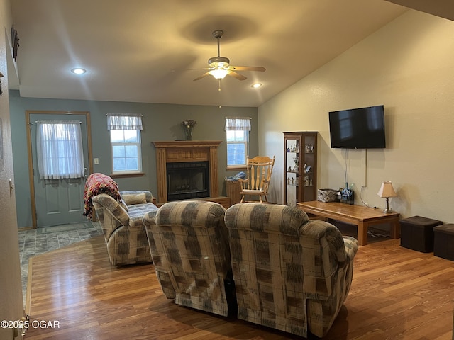 living area featuring a ceiling fan, wood finished floors, vaulted ceiling, a fireplace, and recessed lighting