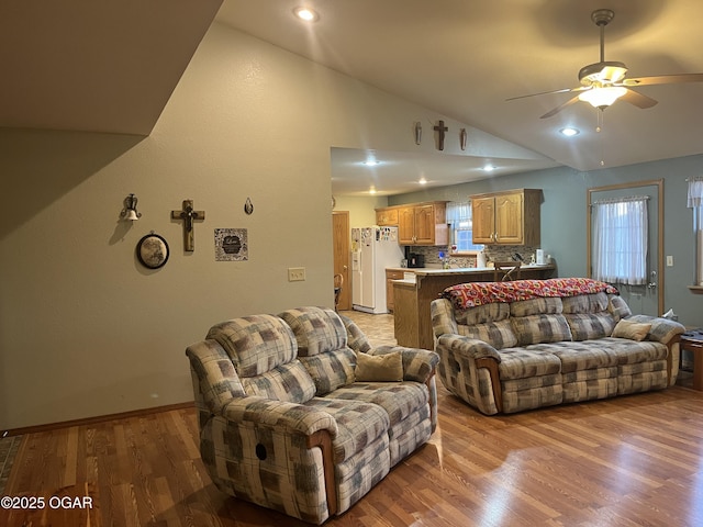 living area with baseboards, ceiling fan, vaulted ceiling, light wood-type flooring, and recessed lighting