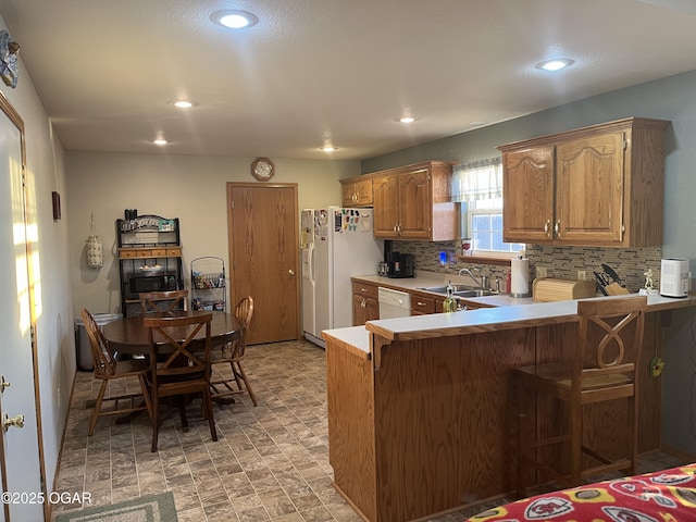 kitchen with light countertops, a breakfast bar, a sink, and tasteful backsplash