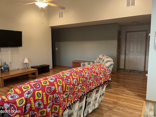 bedroom featuring a ceiling fan, visible vents, and wood finished floors