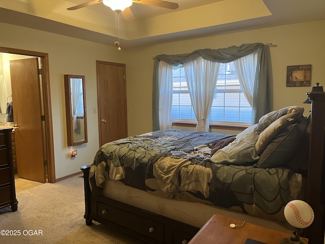 bedroom featuring a ceiling fan, a raised ceiling, light colored carpet, and baseboards