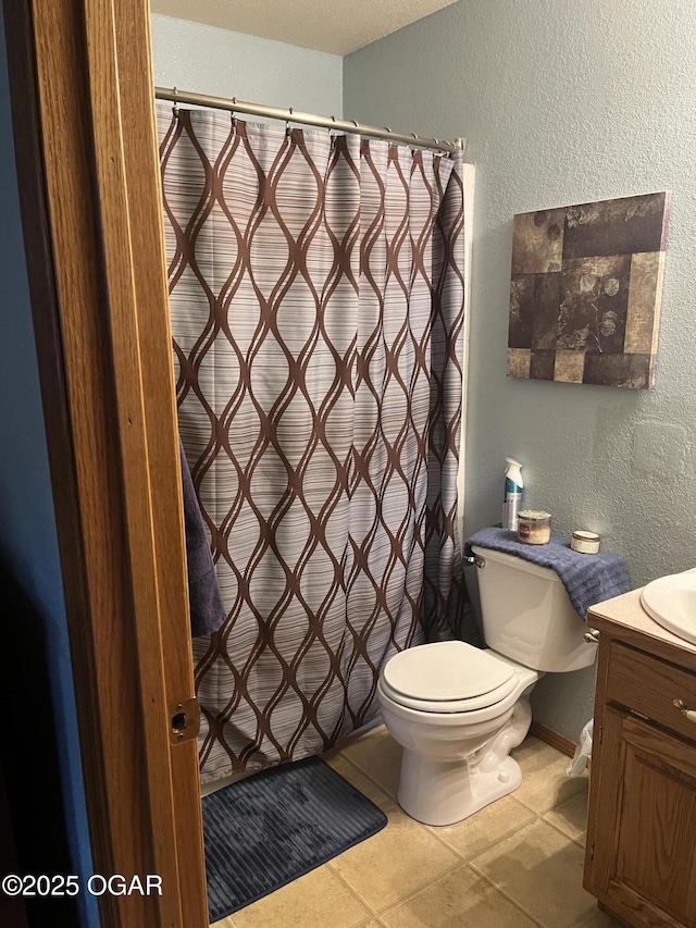 bathroom with curtained shower, a textured wall, toilet, vanity, and tile patterned floors