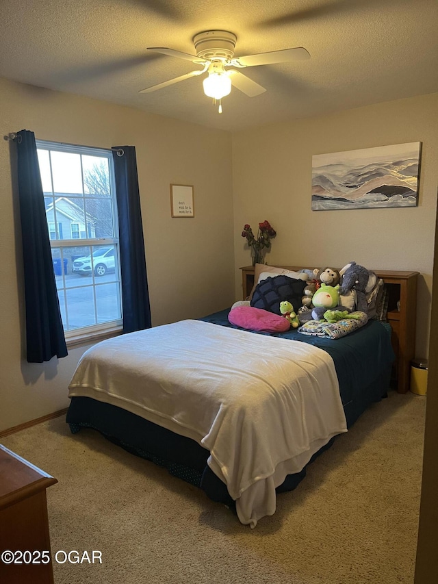 carpeted bedroom featuring a ceiling fan and a textured ceiling