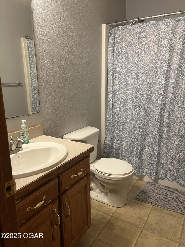 bathroom with a textured wall, toilet, tile patterned floors, curtained shower, and vanity