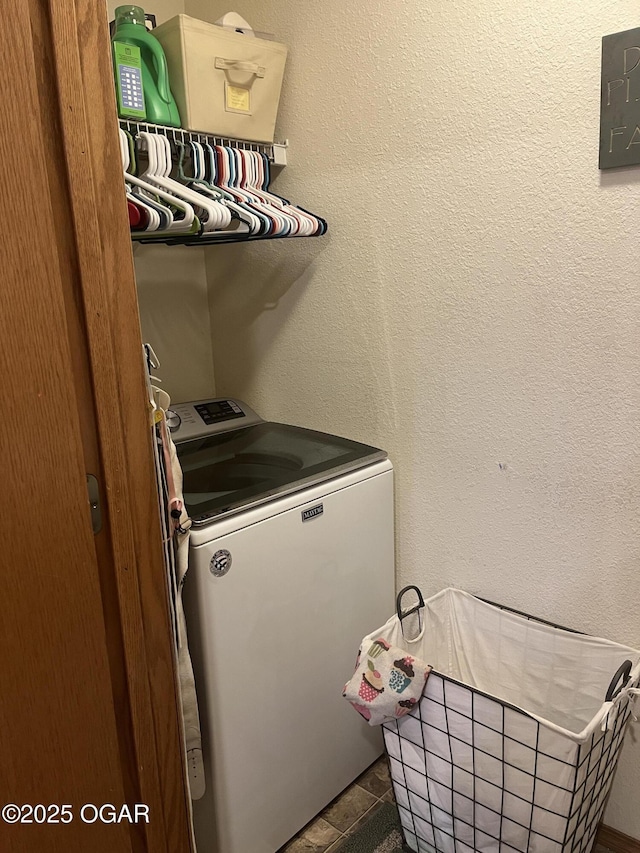 clothes washing area with washer / dryer, laundry area, and a textured wall