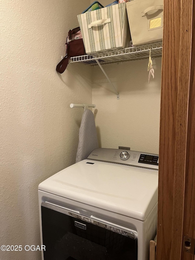 washroom featuring washer / dryer, laundry area, and a textured wall