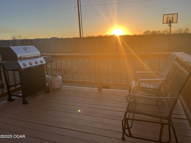 deck at dusk featuring a grill