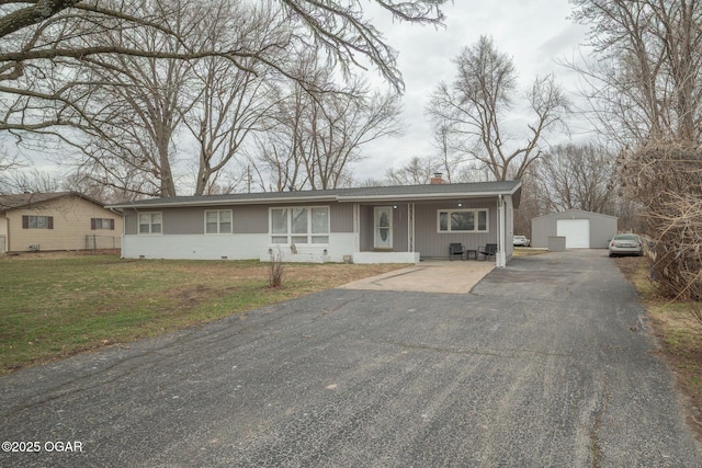 view of front of home featuring an outbuilding, a garage, driveway, a front lawn, and a chimney