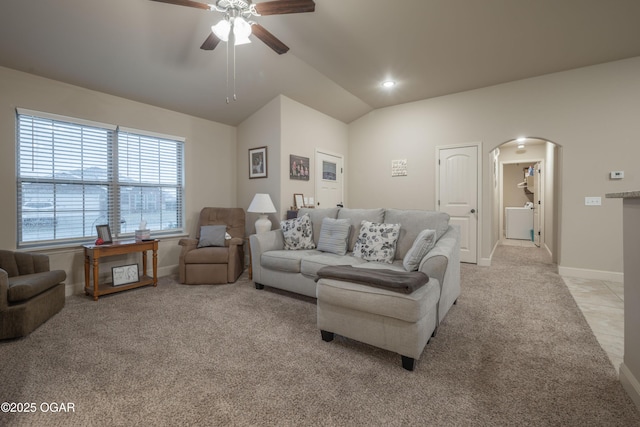 living area featuring lofted ceiling, baseboards, arched walkways, and light colored carpet