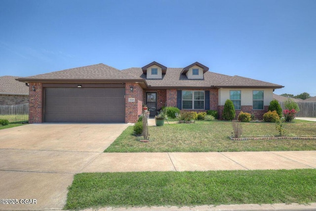 view of front of property featuring brick siding, concrete driveway, a front yard, fence, and a garage