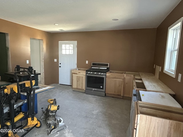 kitchen featuring concrete floors, stainless steel range with gas cooktop, and light brown cabinetry