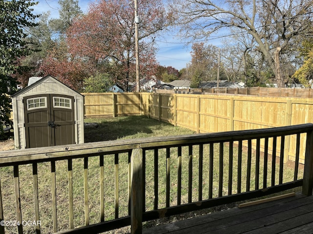 view of yard with a shed, a wooden deck, a fenced backyard, and an outdoor structure