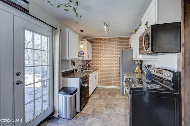 kitchen with white cabinets, dark countertops, brick wall, appliances with stainless steel finishes, and a sink