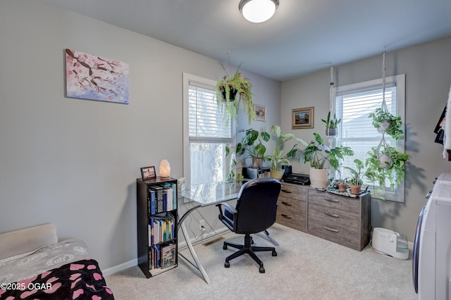 office area featuring baseboards, a healthy amount of sunlight, washer / dryer, and light colored carpet