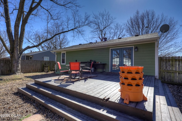 wooden terrace with french doors, outdoor dining area, and fence